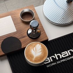 Un latte art posé près du tamper et du porte-filtre